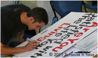 Matt Figueroa, who first visited Occupy Syracuse on Tusday, works on a sign at the site