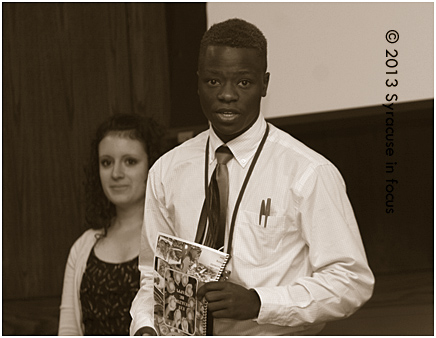 Lugendo Muya and Kirsten Ranallo (background), co-leaders of the Yellow Team of Synterns, present their project details at the Upstate Graduation/Final Boardroom Challenge.