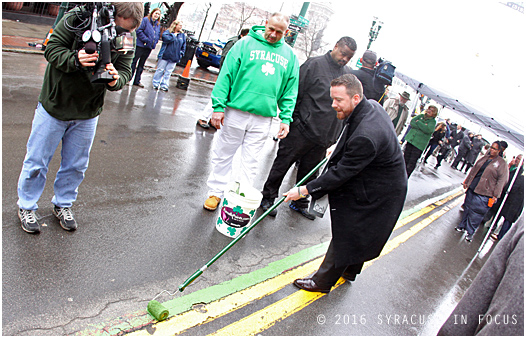 City of Syracuse Director of Policy & Innovation Andrew Maxwell paints a stripe along S. Salina Street ahead of the St. Patrick's Parade, which will be held later today.